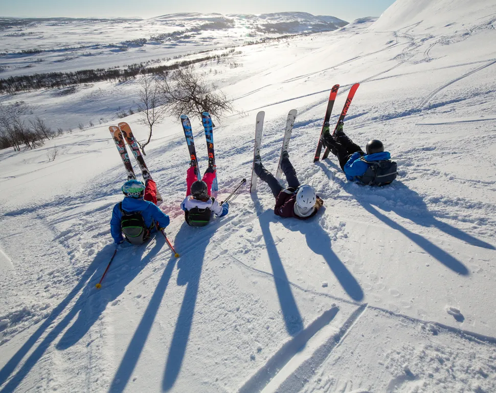 sitter i skidbacken med skidorna uppåt