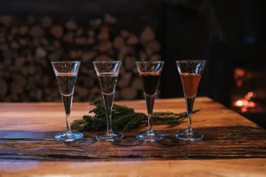 buustasnapsar uppställda på ett bord, granris och brasa i bakgrunden